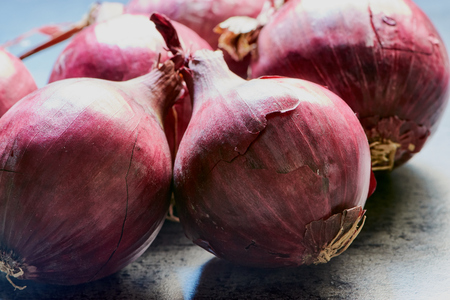 group of fresh red onions on a gray kitchen deskの写真素材