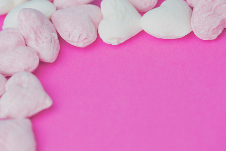 heart-shaped pink and white hard candies on a pink background with copy spaceの写真素材