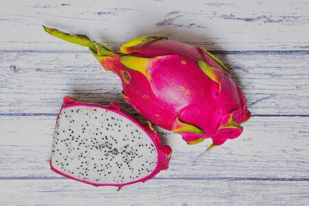 dragon fruit half beside a pink dragon fruit on white wooden backgroundの写真素材