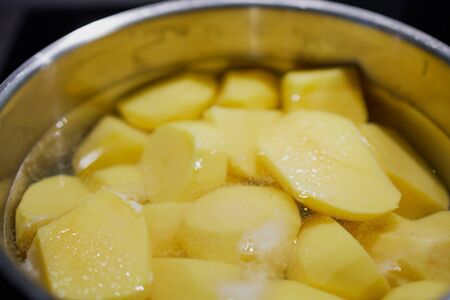 pealed potatoes in a pot with waterの写真素材