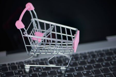 pink miniature shopping cart on a laptop keyboard as concept for online shoppingの写真素材