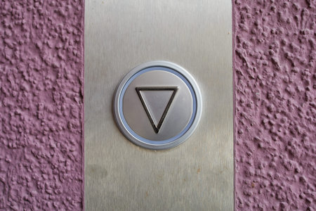 close up of an elevator button on a violet wall