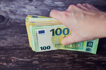 female hand is holding a bundle of Euro banknotes