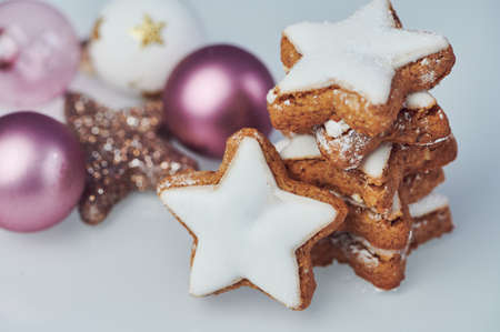 a stack of cinnamon stars on white background beside christmas tree balls, horizontal color photoの写真素材