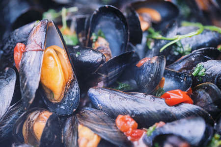 Freshly cooked mussels in a pot, selective focus on the left side on the open musselの写真素材