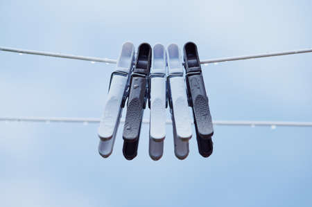 five clothespins on a white clothesline after a rain shower with water dropsの写真素材