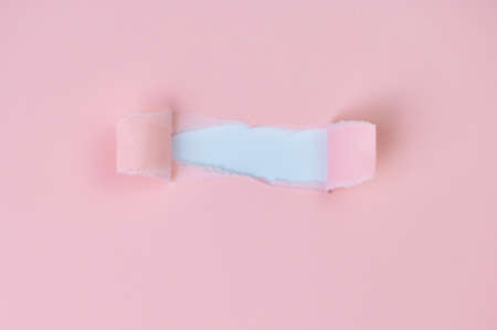 light pink paper torn in the middle, there is a white space for any kind of textの写真素材