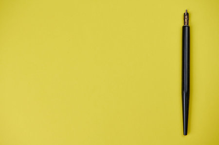 Calligraphy fountain pen lies on the right side on yellow background with copy space