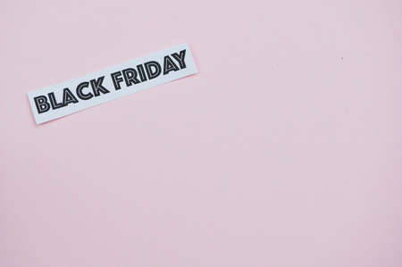 in the left corner a paper wth the words black friday on pink background with copy spaceの写真素材