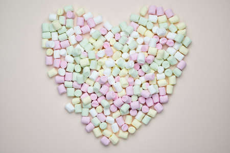 Marshmallows in bright colors lie heart shaped on pastel backgroundの写真素材