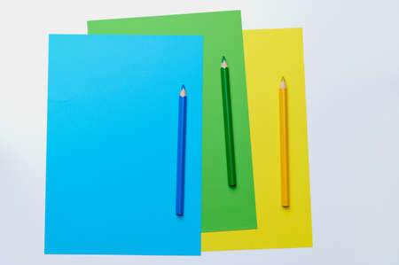 three colored pencils in green, blue and yellow lie on the color matching paper, with copy spaceの写真素材