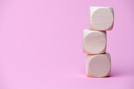 three wooden cubes on each other, copy space for any text, pink background paperの写真素材