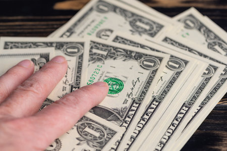 Hand is placing fingers on several dollar bills spread out.の写真素材