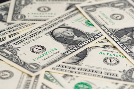 One-dollar bills are scattered on a surface in various positions.