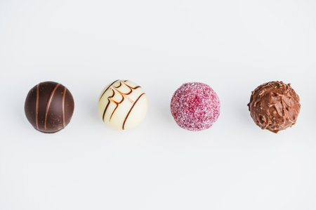 Four chocolate truffles are shown on a plain white surface.の写真素材