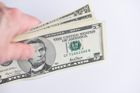 Hand appears to give five dollar bills for a tradeの写真素材