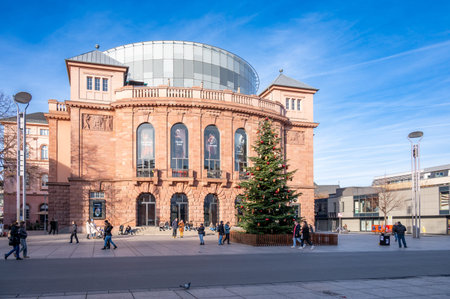 Mainz, Germany - December 22, 2025: People walk near a Christmas tree by theater of Mainz in winter.