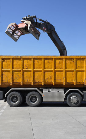  Demolition claw dumping material into a waiting truck.