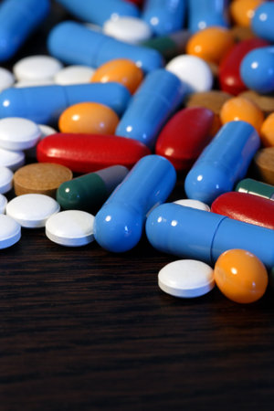 Collection of assorted pills on a dark wood table.