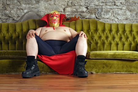Photograph of a Mexican wrestler or Luchador sitting on a green couch waiting for his match to begin.の写真素材