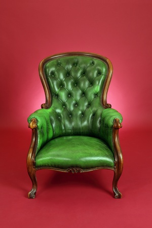 old antique green leather chair sitting on a red background.の写真素材
