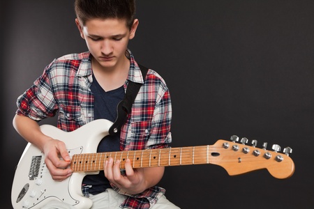 Photo of a teenage male playing a white electric guitar.の写真素材