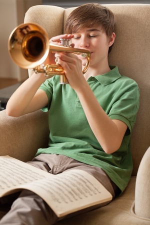 Photo of a teenage male practicing his trumpet at home. Focus on face of boy.の写真素材