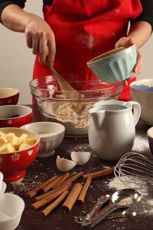 Photo of a female mixing ingredients in a large glass bowl. Could be muffins, cookies, bread, etc.