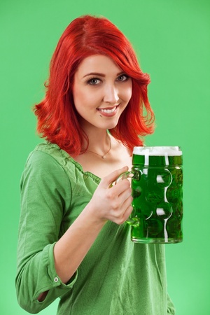 Photo of a beautiful redhead holding a huge mug of green beer for St. Patricks Day celebrations.の写真素材