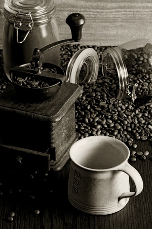 Photo of roasted coffee beans, coffee cup, antique grinder on a wooden table.の写真素材