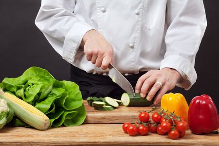 Photo of a chef chopping vegetables on a wooden cutting board.の写真素材