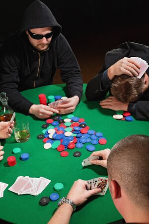 Photo of four men playing poker with one player frustrated. Focus is on the winning poker hand.の写真素材