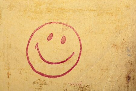 Photo of a vintage happy face stamp on old scratched worn paper.の写真素材