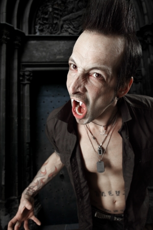 a male vampire with mouth open and fangs showing.  Harsh lighting and heavily filtered for scarier feel.の写真素材