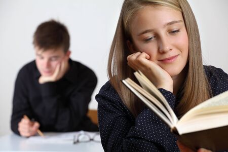 Photo of a young student reading a book in her classroom.の写真素材