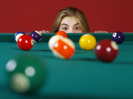 Photo of a young girl checking the billiard balls for a chance at a good shot.の写真素材