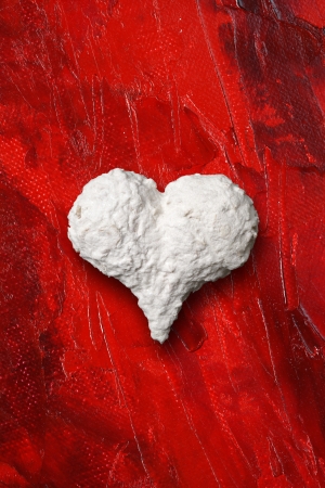 Photo of a white heart on top of red painted background の写真素材