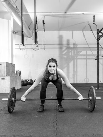 Photo of a young woman at a crossfit gym lifting a barbell.の写真素材