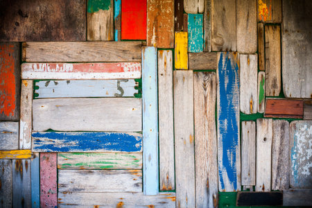 Photo of a well worn wooden wall with multicoloured planks and vignetting added.の写真素材