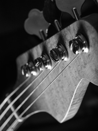 Black and white photo of a bass guitar headstock over black background.の写真素材