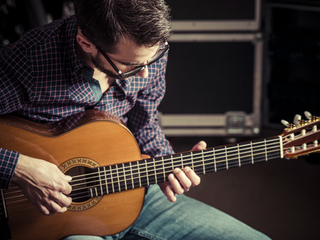 Photo of a man playing his acoustic guitar in a rehearsal studio. Focus on manâs head.の写真素材