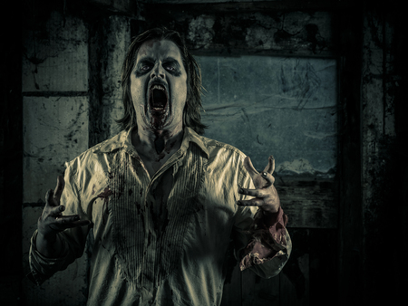 Photo of a hungry zombie staring at you in a dark scary room.の写真素材
