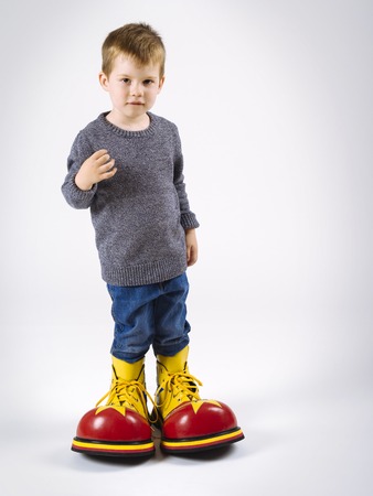 Photo of a young boy wearing huge clown shoes.の写真素材