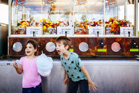 Photo of a brother and sister eating a big cotton candy at an amusement park.の写真素材