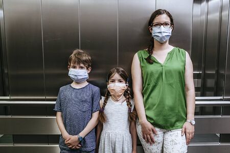 Mother and her two children wearing protective masks during covid-19 pandemic.の写真素材