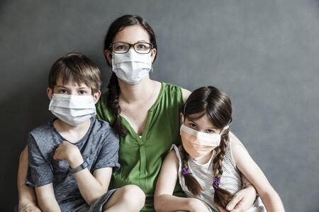 Mother and her two children wearing protective masks during covid-19 pandemic.の写真素材