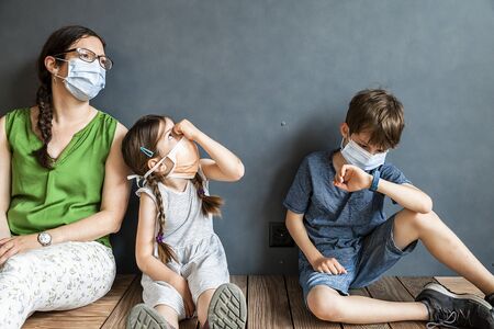 Mother and her two children wearing protective masks during covid-19 pandemic.の写真素材