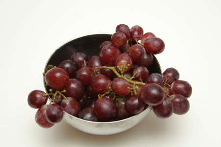 a bowlful of red grapes isolated on whites shot from slightly above and to the sideの写真素材