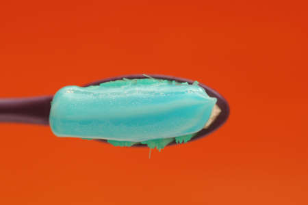 toothbrush with toothpaste isolated on orange background shown from topの写真素材