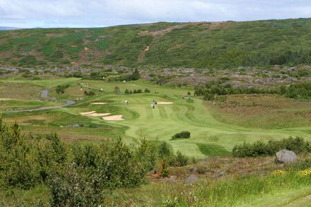 A green golfcourse on a overcast day, people on the greens playing golfの写真素材